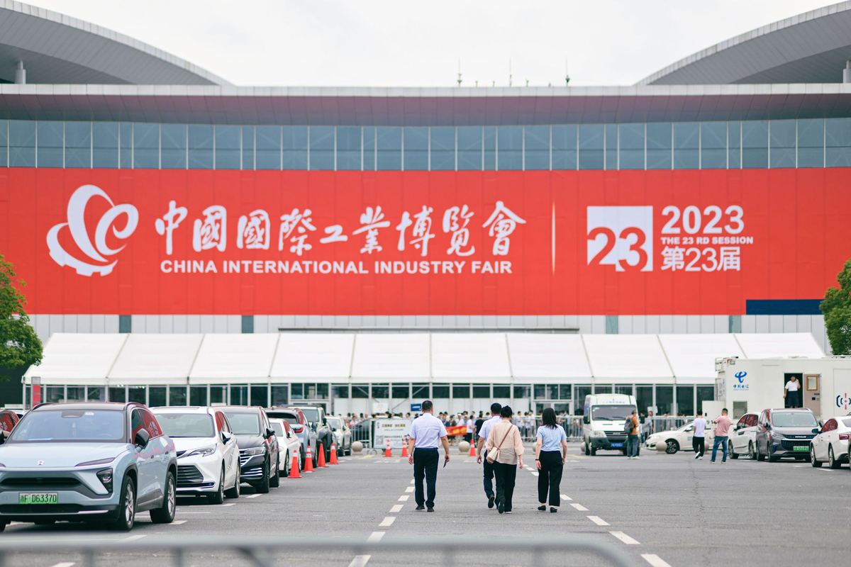 Buyers walking towards the entrance of the China International Industry Fair in Shanghai, under the fair banner