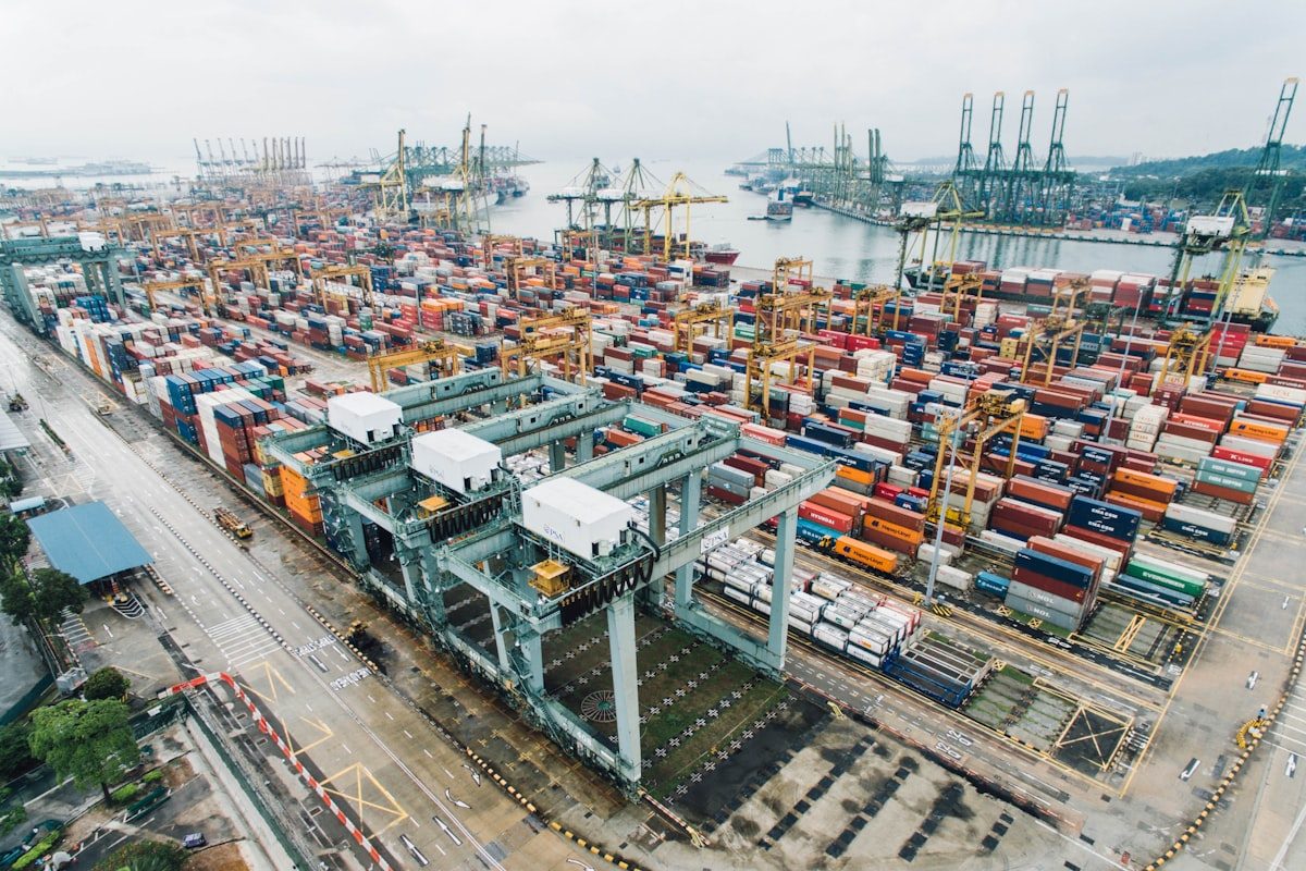 A container terminal seen from above, stacked with thousands of shipping containers and gantry cranes