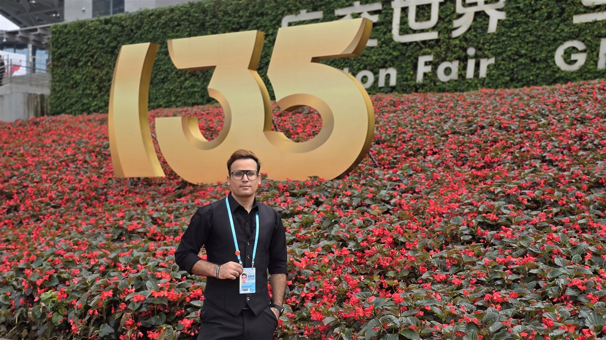 Hidayat Khan in front of the Canton Fair 135th session gold logo and red begonia display, spring 2024